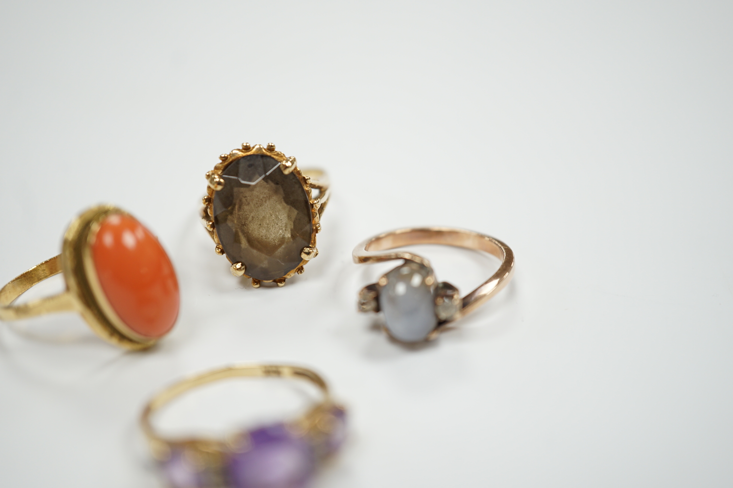 Two modern 10k and gem set rings, including amethyst and diamond chip and two yellow metal and gem set rings including coral set and star quartz? set, gross weight 15.9 grams.